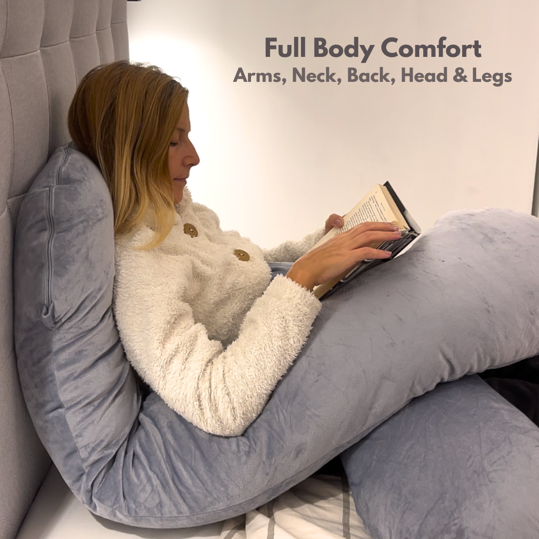 Woman reading in bed propped on the Cuddly Pillow™, full body comfort for arms, neck, back and legs