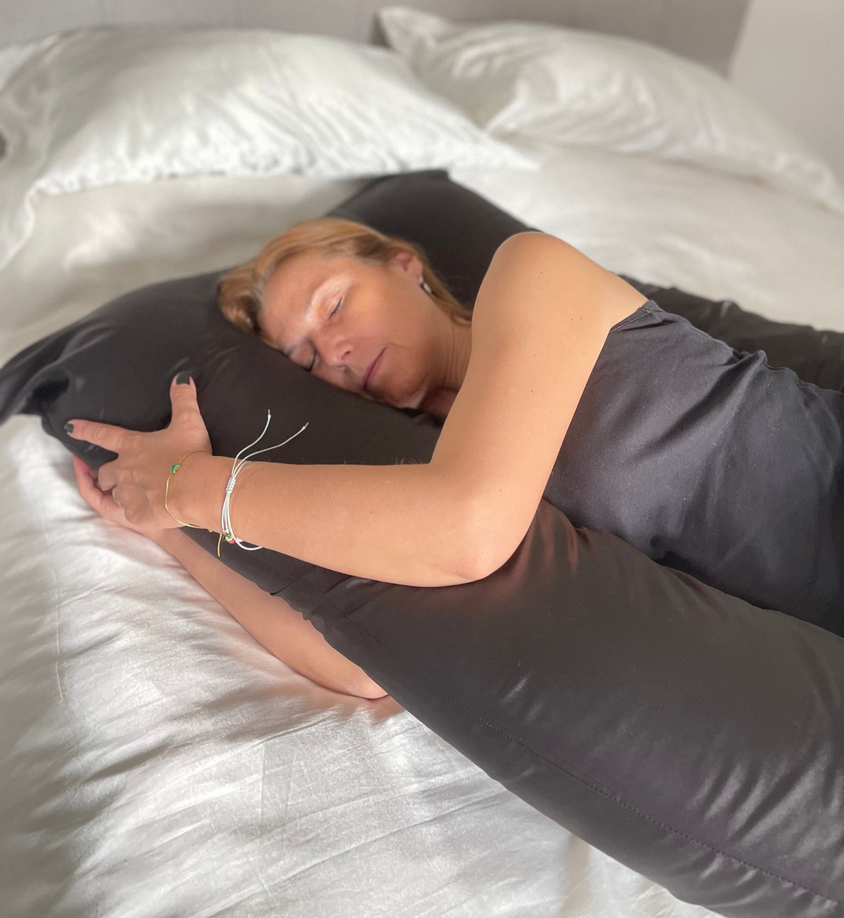 Woman sleeping on a Cuddly Pillow™ with the black Cooling Silk Cover