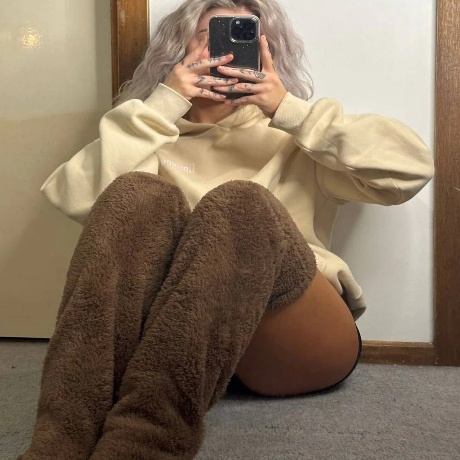 Woman sitting on the floor wearing brown thigh-high Fuzzy Socks™ by The Snuggles