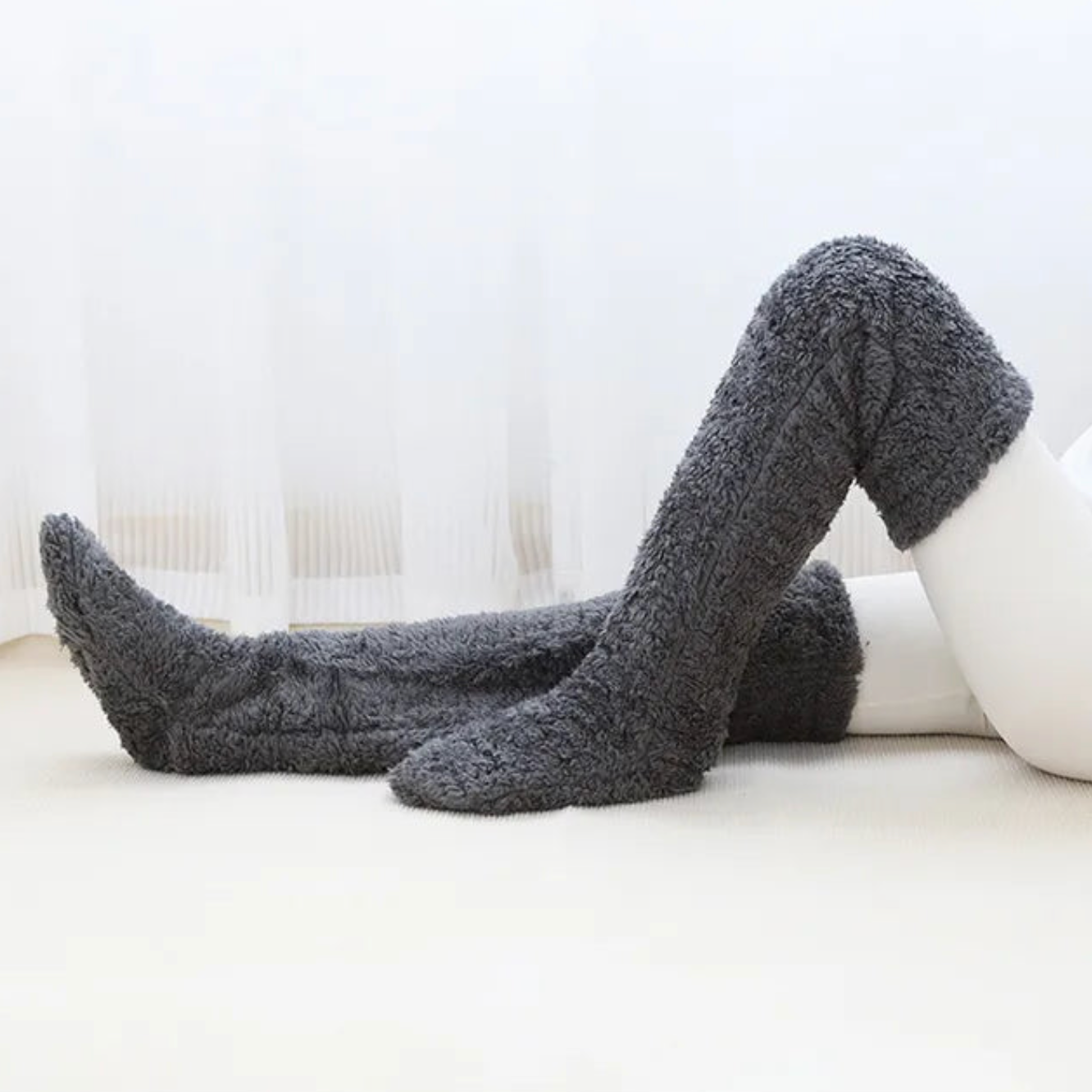 Grey over-the-knee Fuzzy Socks™ by The Snuggles on a white floor