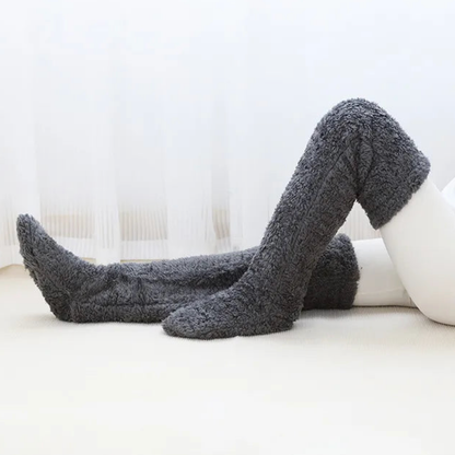 Grey over-the-knee Fuzzy Socks™ by The Snuggles on a white floor
