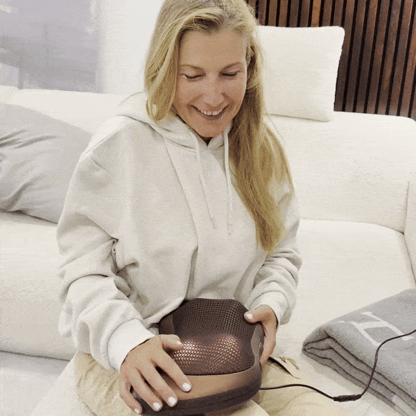 Woman on a sofa holding the Neck & Back Massager