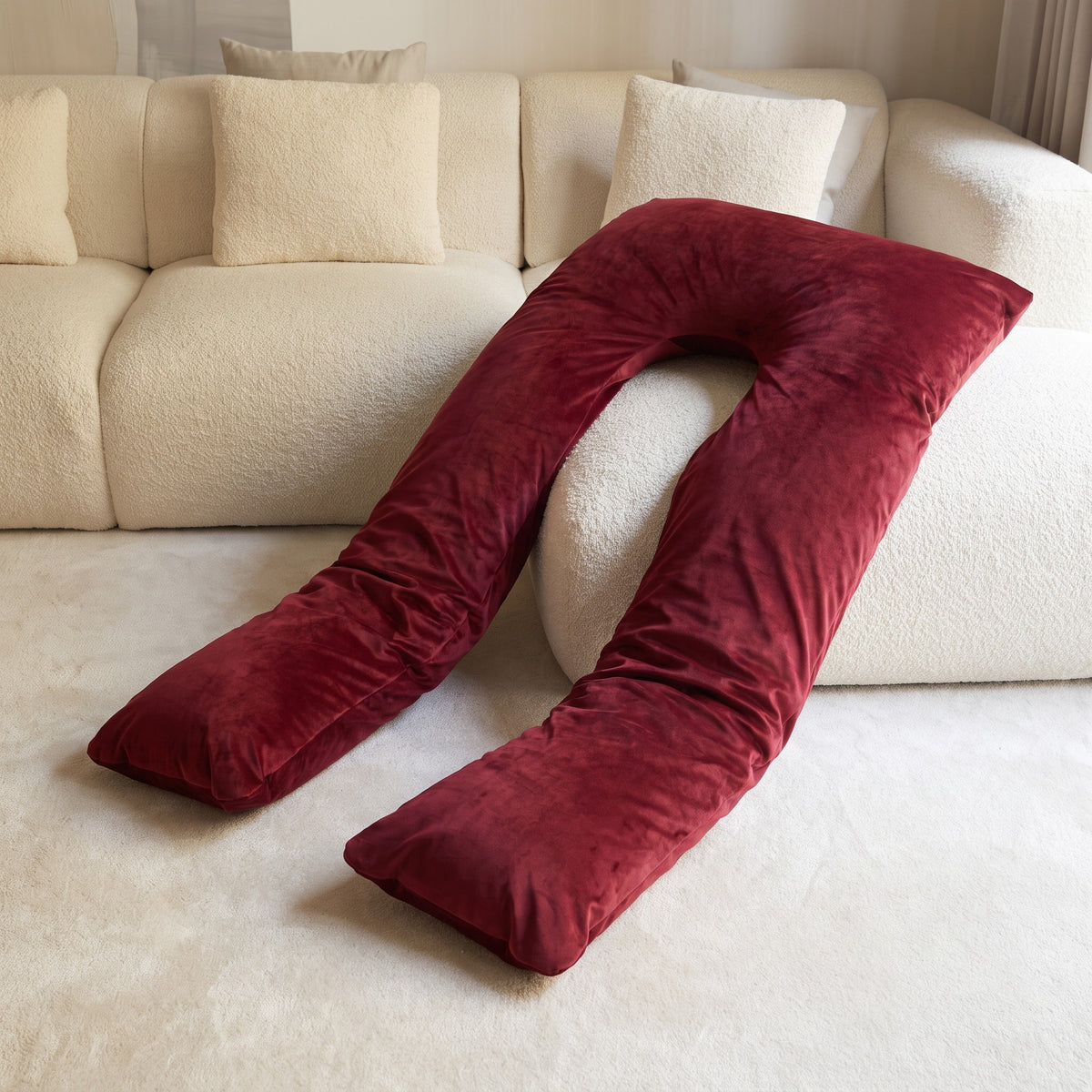 Cuddly Pillow in the Red Satin Silk Cover resting on a cream boucle sofa