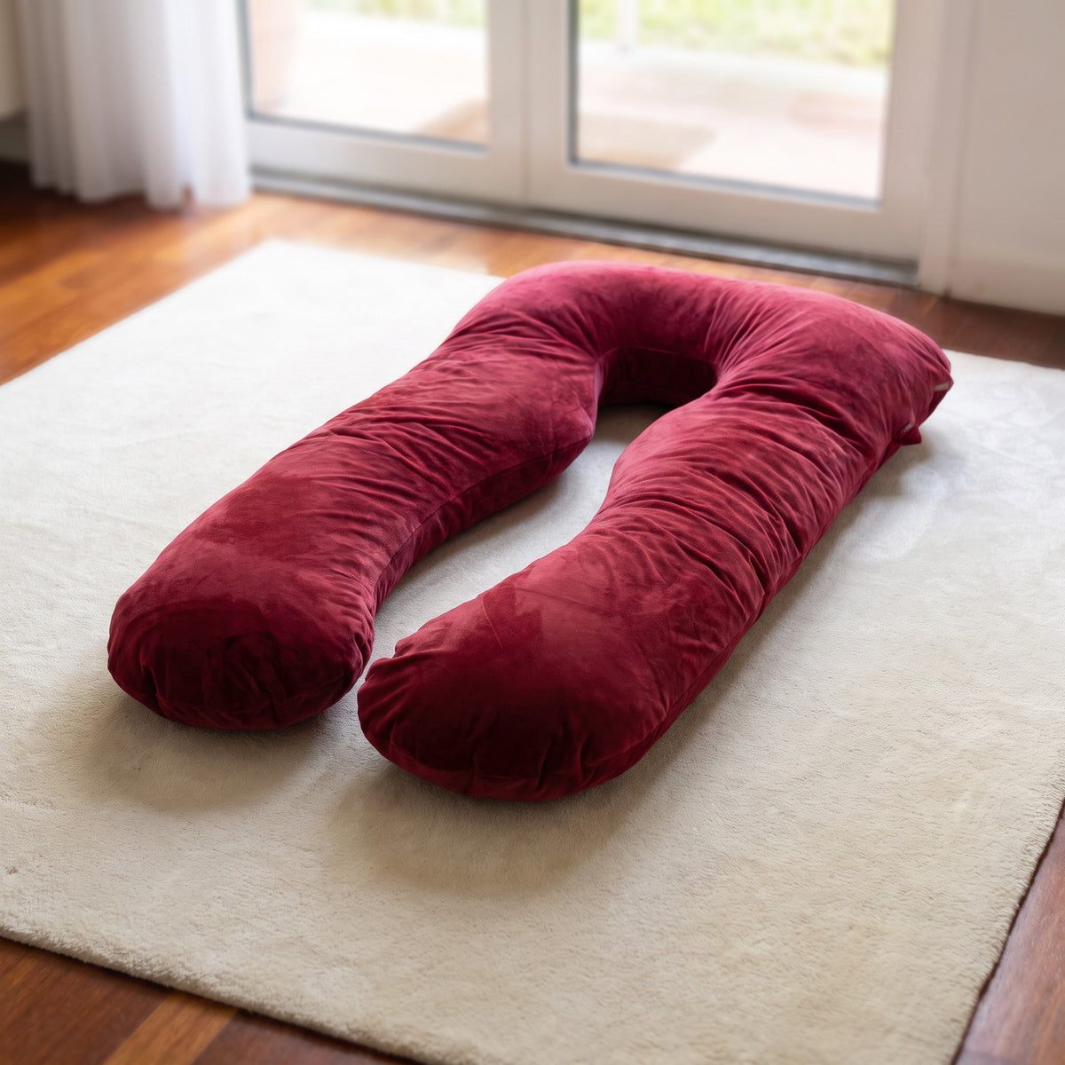 Deep wine-red satin silk Cuddly Pillow cover on a cream rug in a bright living room