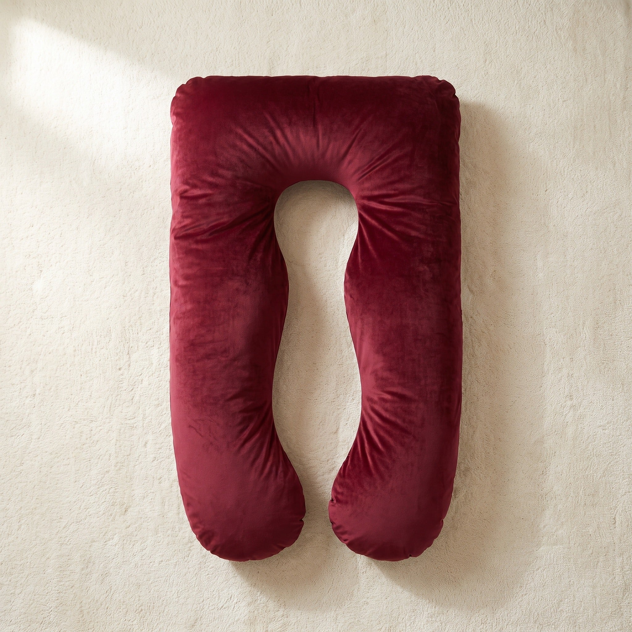 Red Satin Silk Cover on a U-shaped Cuddly Pillow, overhead view on an ivory rug