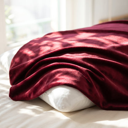 Wine-red satin silk fabric draped in soft folds in morning sunlight