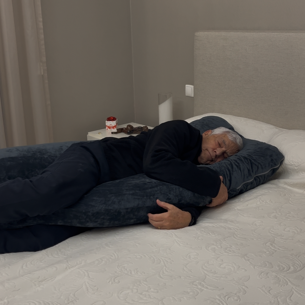 Man resting on The Sidelock Pillow™ body pillow across a bed