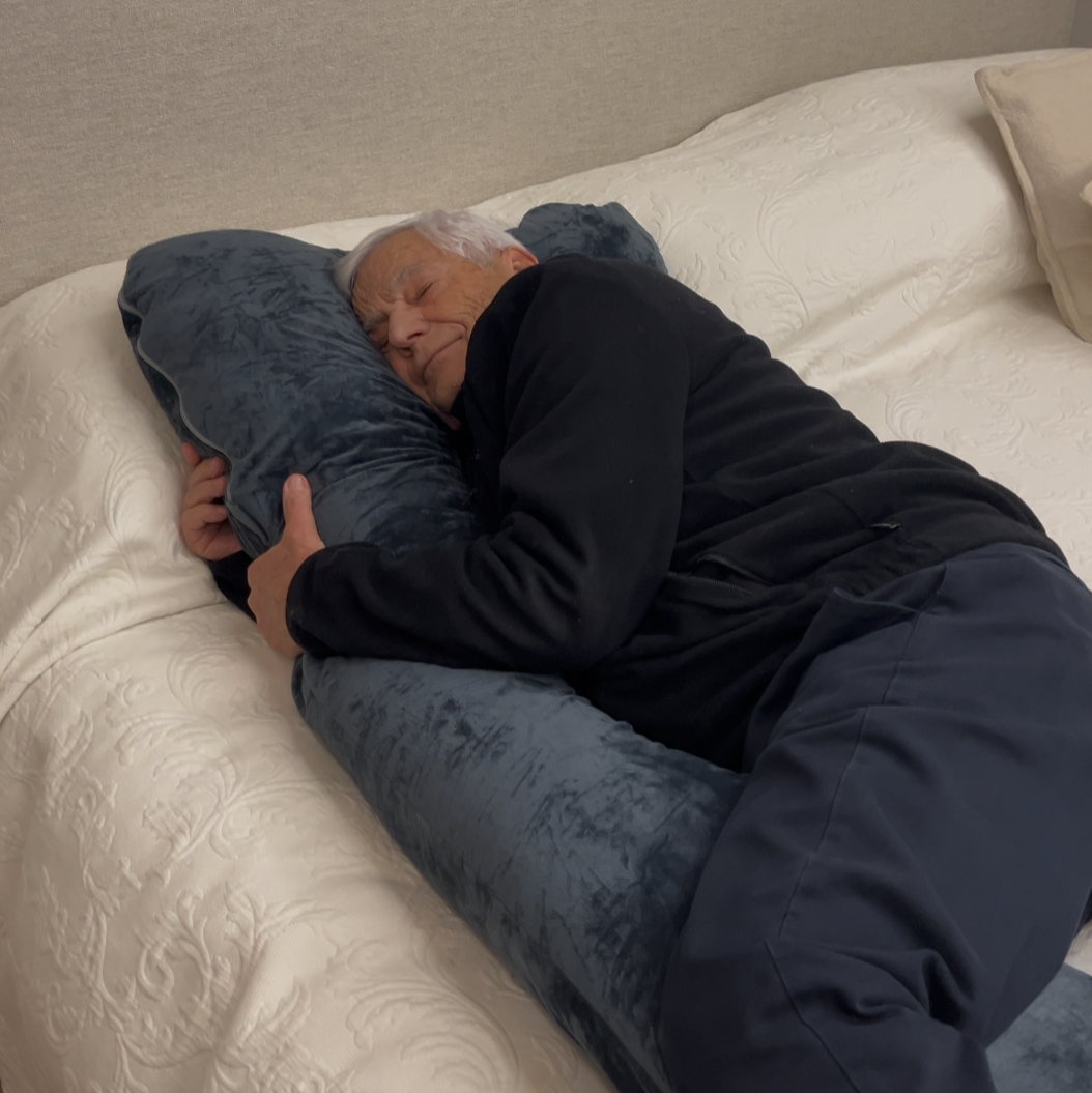 Man side sleeping in bed hugging The Sidelock Pillow™ by The Snuggles